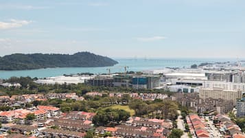 A coastal cityscape with residential buildings, a bridge, and a forested island.