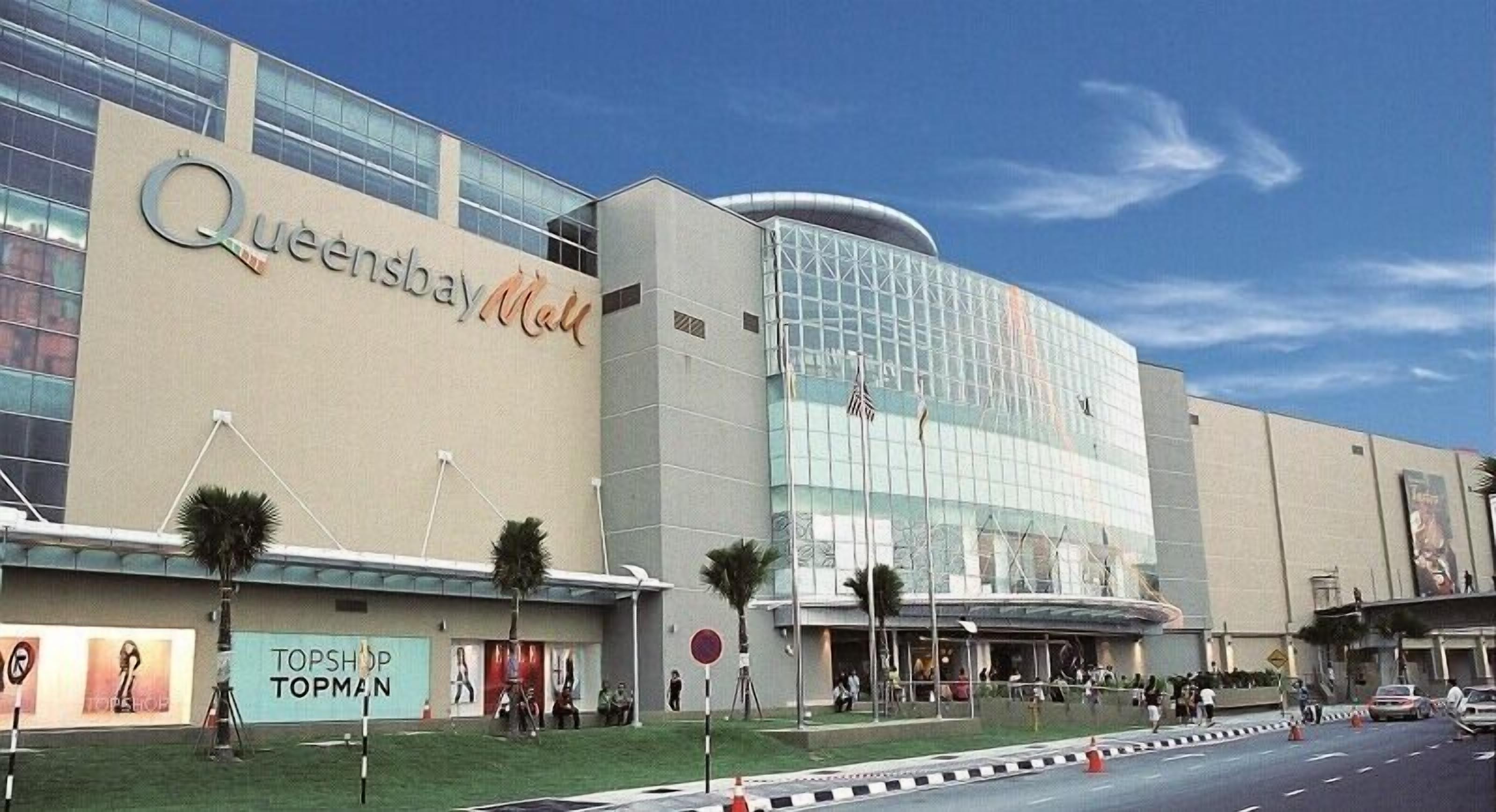 A large, modern building with the sign 'Queensbay Mall' prominently displayed.