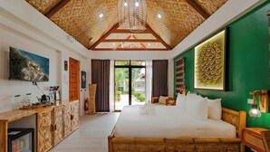 A bedroom with a large bed, a wooden cabinet, a television, and a green accent wall. - Casa Verde Cliff Resort and Spa (San Francisco)