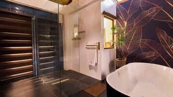 Un baño moderno con ducha envuelta en vidrio, una bañera grande y un revestimiento de pared con diseño de hojas.