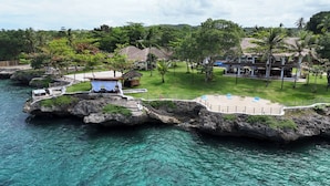 A resort with a rocky island, clear turquoise water, and a grassy area with seating. - Casa Verde Cliff Resort and Spa (San Francisco)
