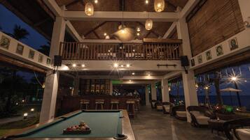 An indoor pool area with a bar, lounge chairs, and a view of the ocean.