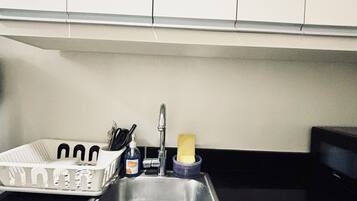 Een koelkast, een magnetron, een kookplaat, kookgerei, borden en bestek