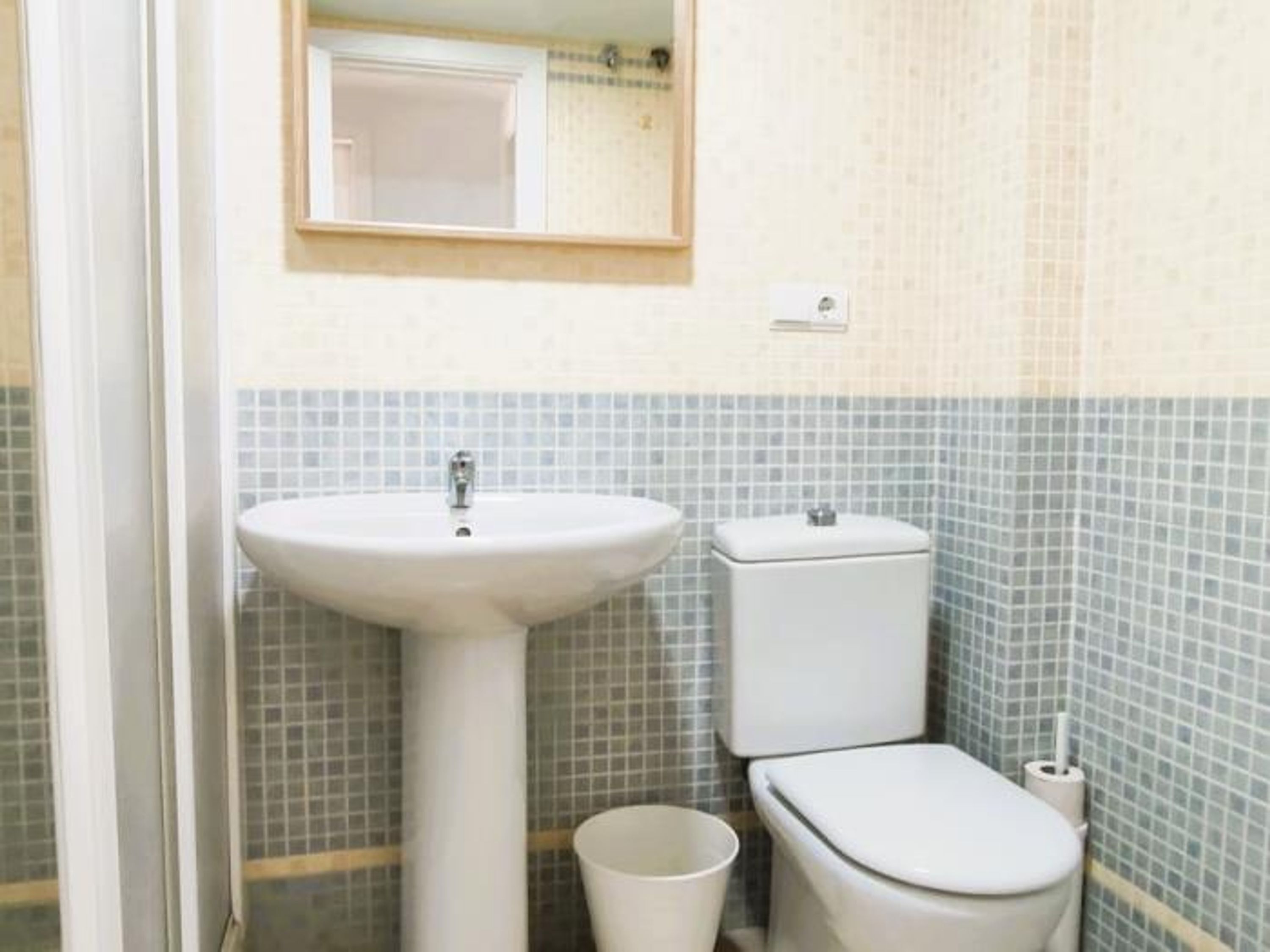 A bathroom with a sink, toilet, and a mirror.