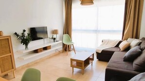 A modern living room with a sofa, a television, a dining table, and a chair. - Smart Conil los Bateles 28584 (Conil de la Frontera)