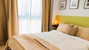 A neatly made bed with a beige and white duvet, a bedside table with a lamp, and a wall with framed pictures. - Smart Conil los Bateles 28584 (Conil de la Frontera)