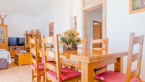 A dining area with a wooden table and chairs, a television, and a decorative plant. - Casa Mariana 1417 in Conil de la Frontera (Conil de la Frontera)