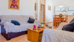 A living room with a sofa, a coffee table, and a dining area with chairs and a table. - Casa Mariana 1417 in Conil de la Frontera (Conil de la Frontera)