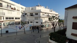 Un edificio de varios pisos con balcones, un paseo peatonal y vistas al mar.