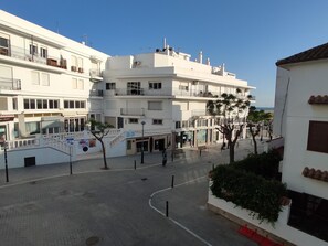 Ein mehrstöckiges Gebäude mit Balkonen, einem Fußgängerweg und Blick auf das Meer.