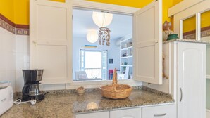 A kitchen with white cabinets, a granite countertop, and a coffee maker. - Balc n Atl Ntico 27786 (Conil de la Frontera)