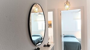 Una camera da letto con un letto, una cassettiera, uno specchio e due lampade a sospensione.