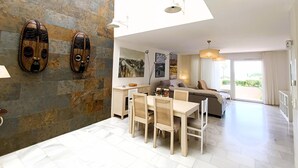 Una sala de estar moderna con comedor, un sofá y un ventanal grande.