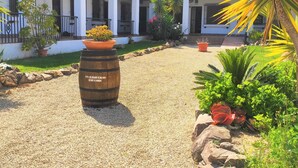 A courtyard with a gravel path, potted plants, and a barrel with text.