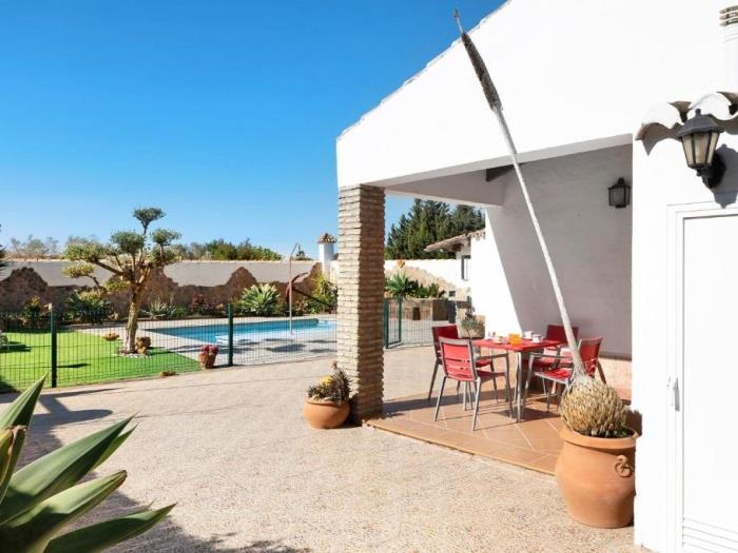 Un espace extérieur abrité avec une piscine, des chaises rouges et des plantes en pot.