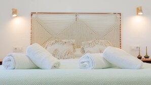 A bed with a woven headboard, two bedside lamps, and rolled towels on the bed. - Moon Villa in Conil de la Frontera (Conil de la Frontera)
