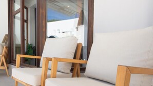 A wooden chair with a cushion in a room with a large window. - Moon Villa in Conil de la Frontera (Conil de la Frontera)