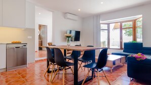 A modern kitchen with white cabinets, a dishwasher, and a dining area with a wooden table and black chairs. - Moon Villa in Conil de la Frontera (Conil de la Frontera)