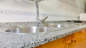 Eine Küche mit Granit Arbeitsplatte, Edelstahl-Spüle und einer Spritzschutzwand mit blauen und weißen Fliesen.