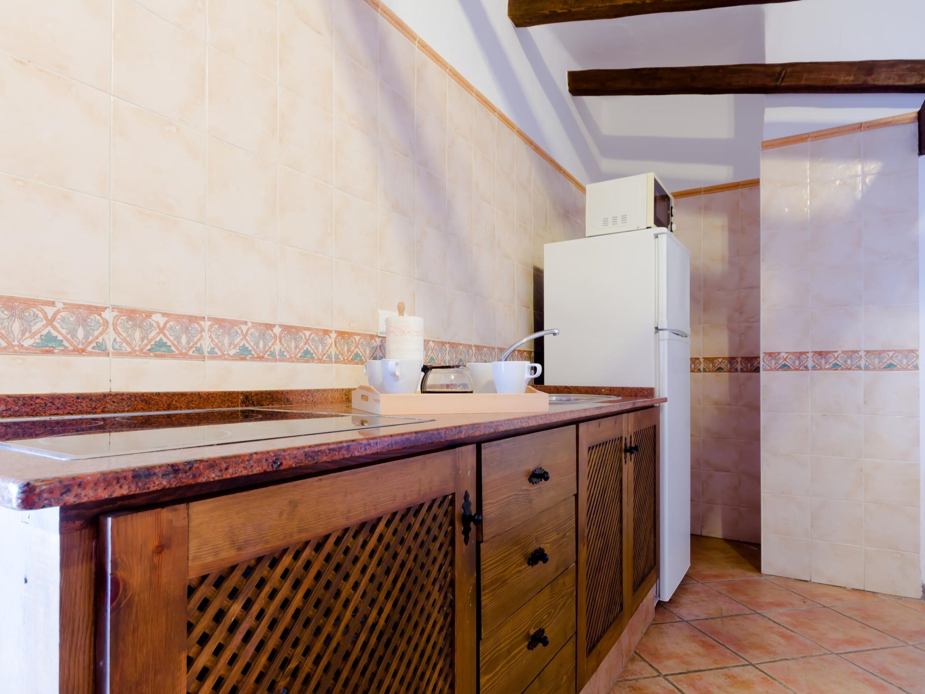 A kitchen with a wooden countertop, a sink, a white refrigerator, and patterned backsplash tiles.