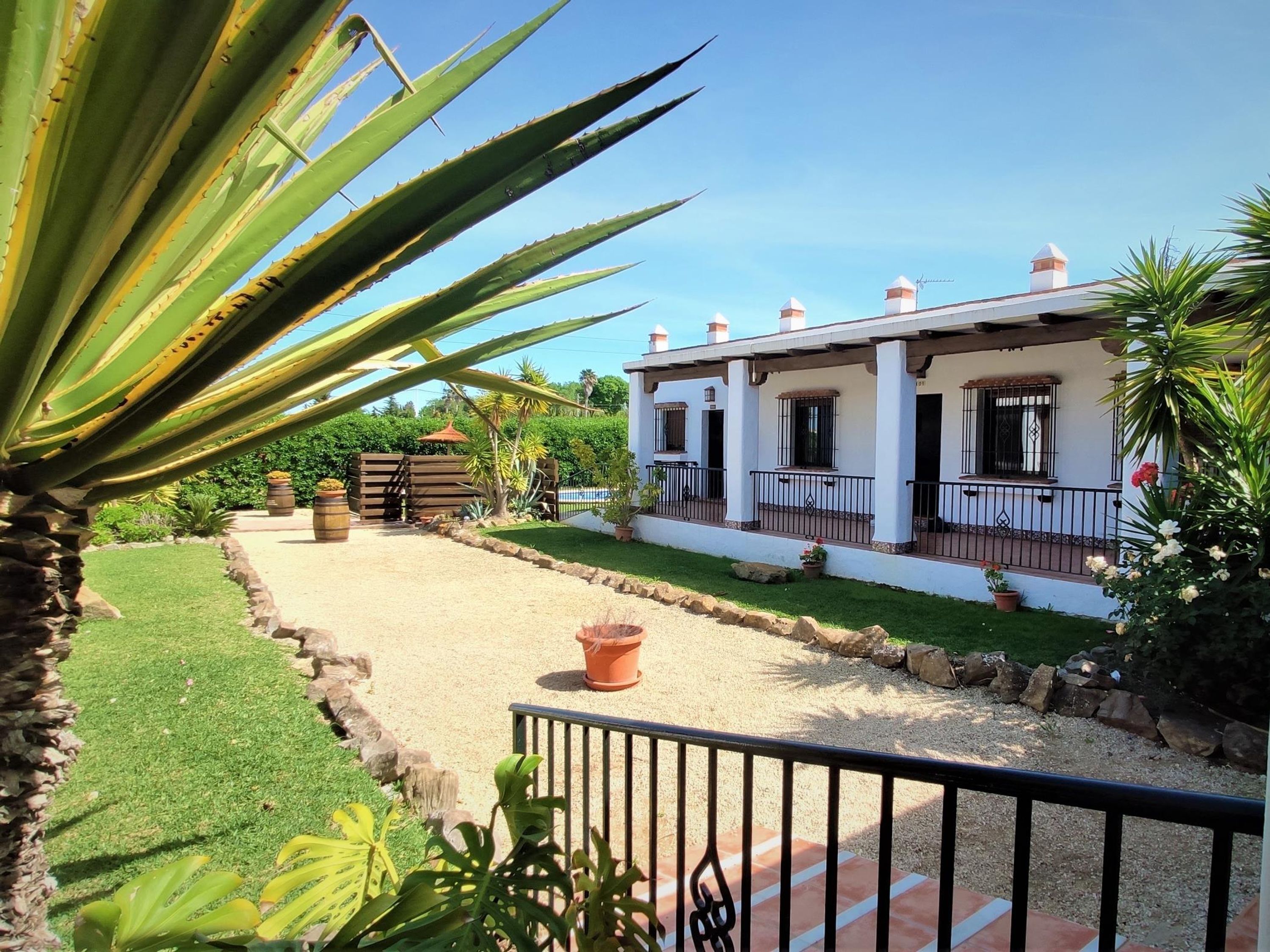 A white building with a covered patio and a gravel pathway.