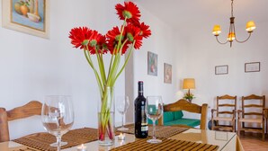 En matplats med ett bord dukat för två personer, med en vinflaska, glas och en vas med röda blommor.