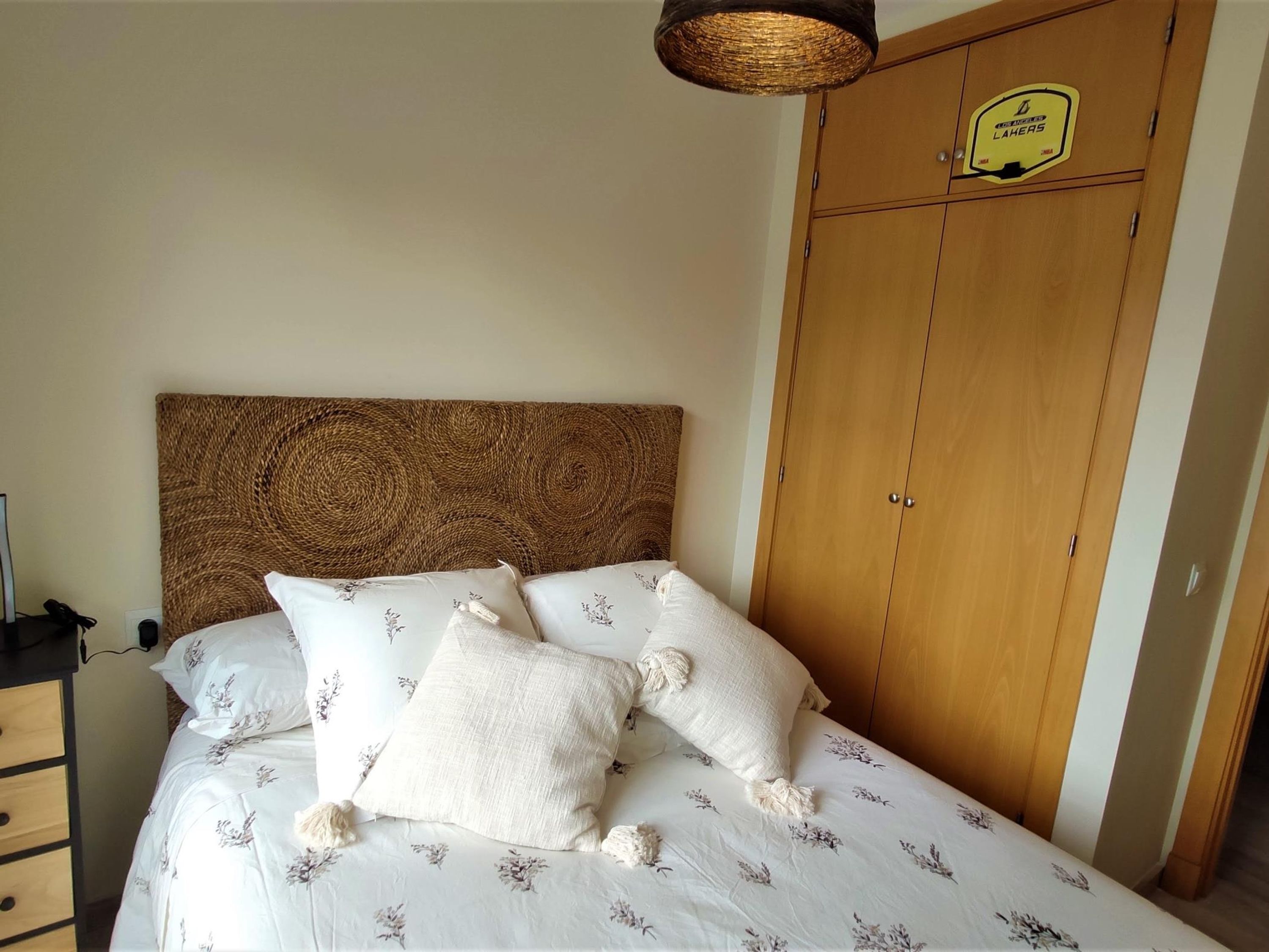 Une chambre à coucher avec un lit, une armoire en bois et un luminaire suspendu.