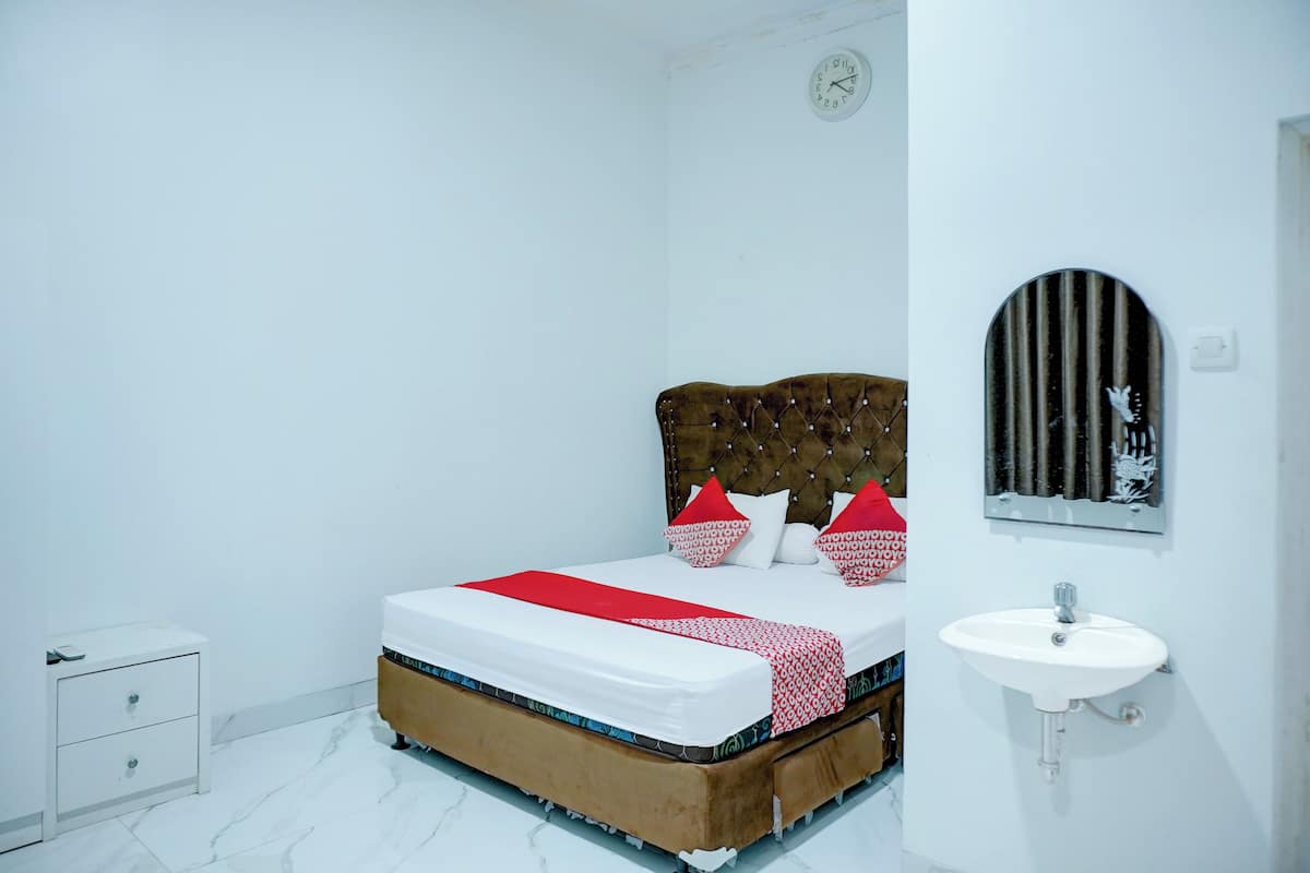 Une chambre à coucher comprenant un lit, une table de chevet, une horloge murale, un miroir et un lavabo.