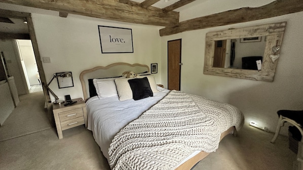 A bedroom with a bed, bedside table, lamp, and a framed picture on the wall.