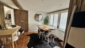 A dining area with a wooden table, chairs, a mirror, and a potted plant.