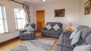 Ein Wohnzimmer mit grauen Sofas, einer Holztür und einem Gemälde an der Wand.