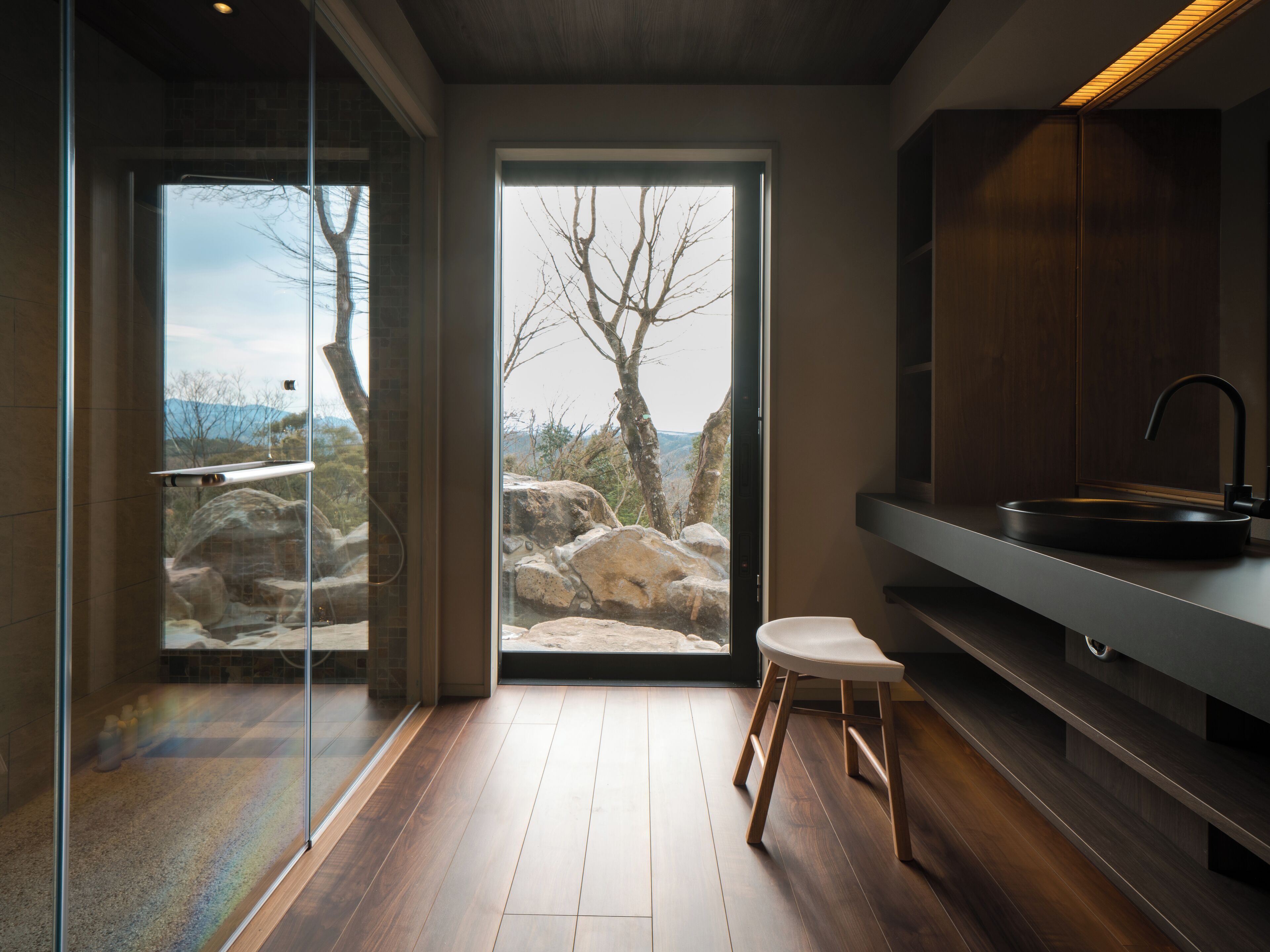 A modern bathroom with a large glass door leading to a scenic outdoor view.