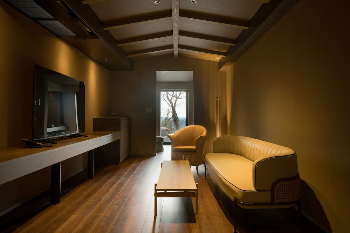 A modern living room with a wooden floor, a sofa, a TV, and a small table.