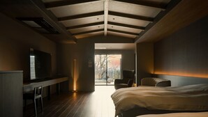 A modern bedroom with a large bed, a desk, and a television. - Kirinosato (Kirishima)