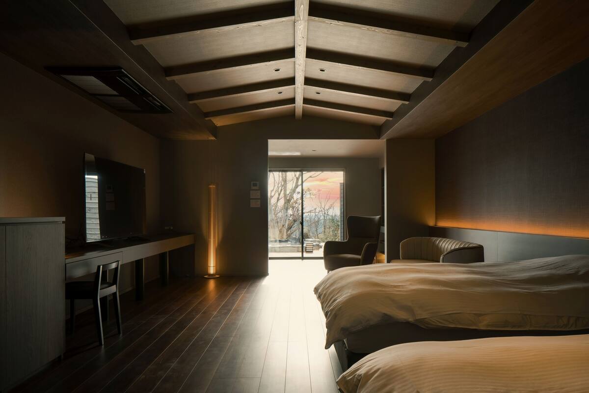 A modern bedroom with a large bed, a desk, and a television.
