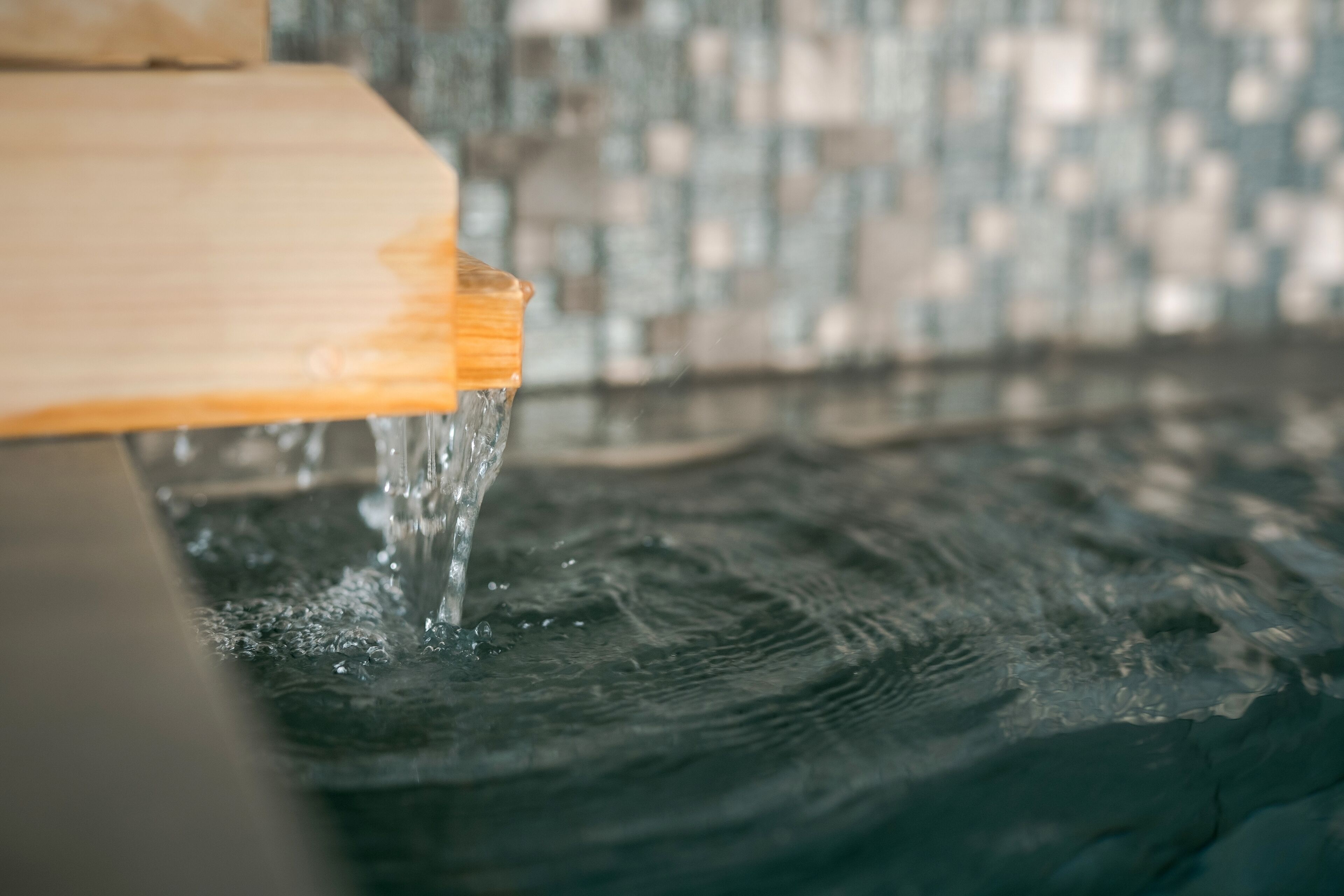 Un gros plan d’eau qui coule d’un robinet en bois sur une surface texturée.