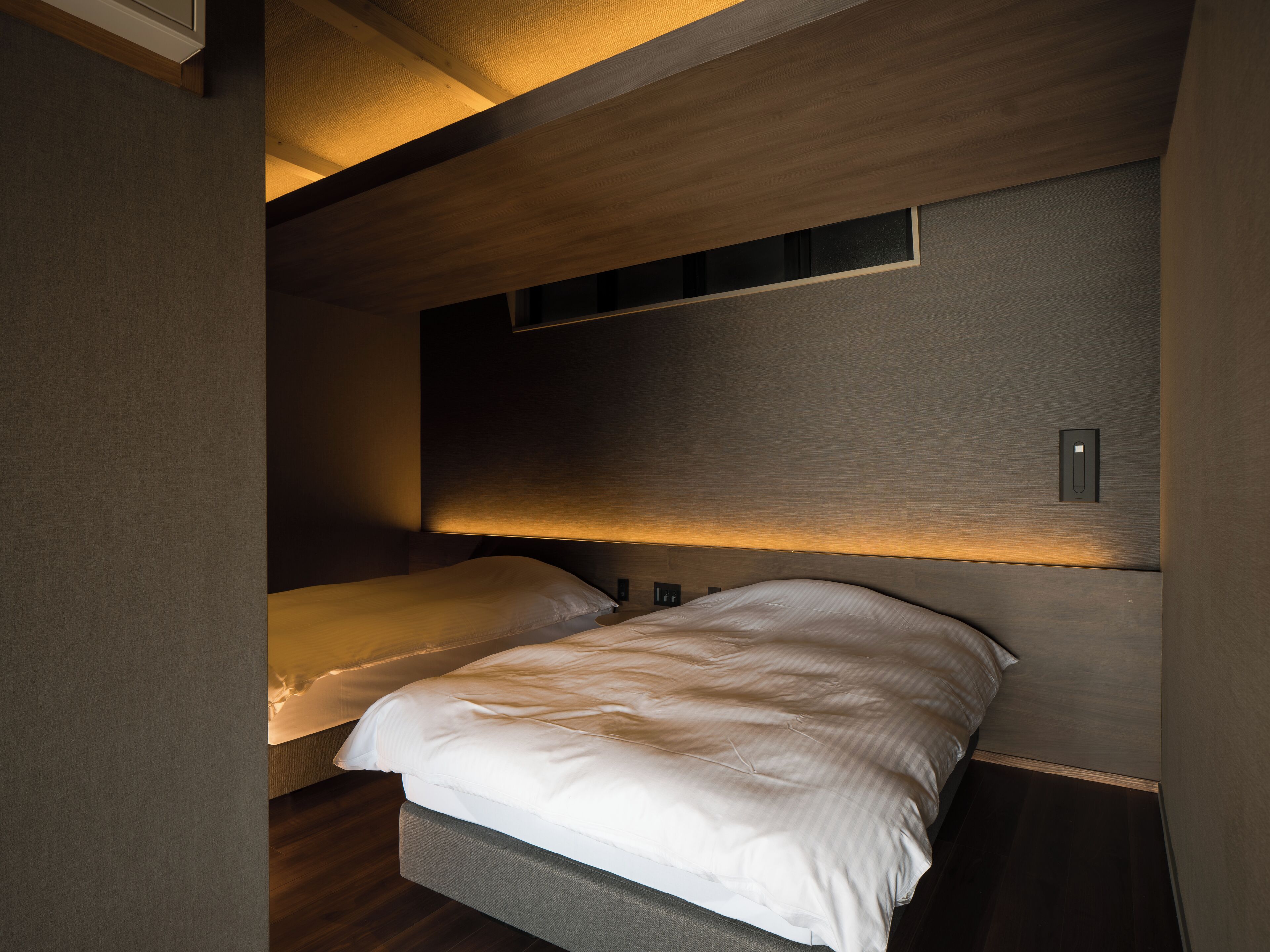 Ein modernes Schlafzimmer mit Bett, Kopfteil und eingebautem Regal.