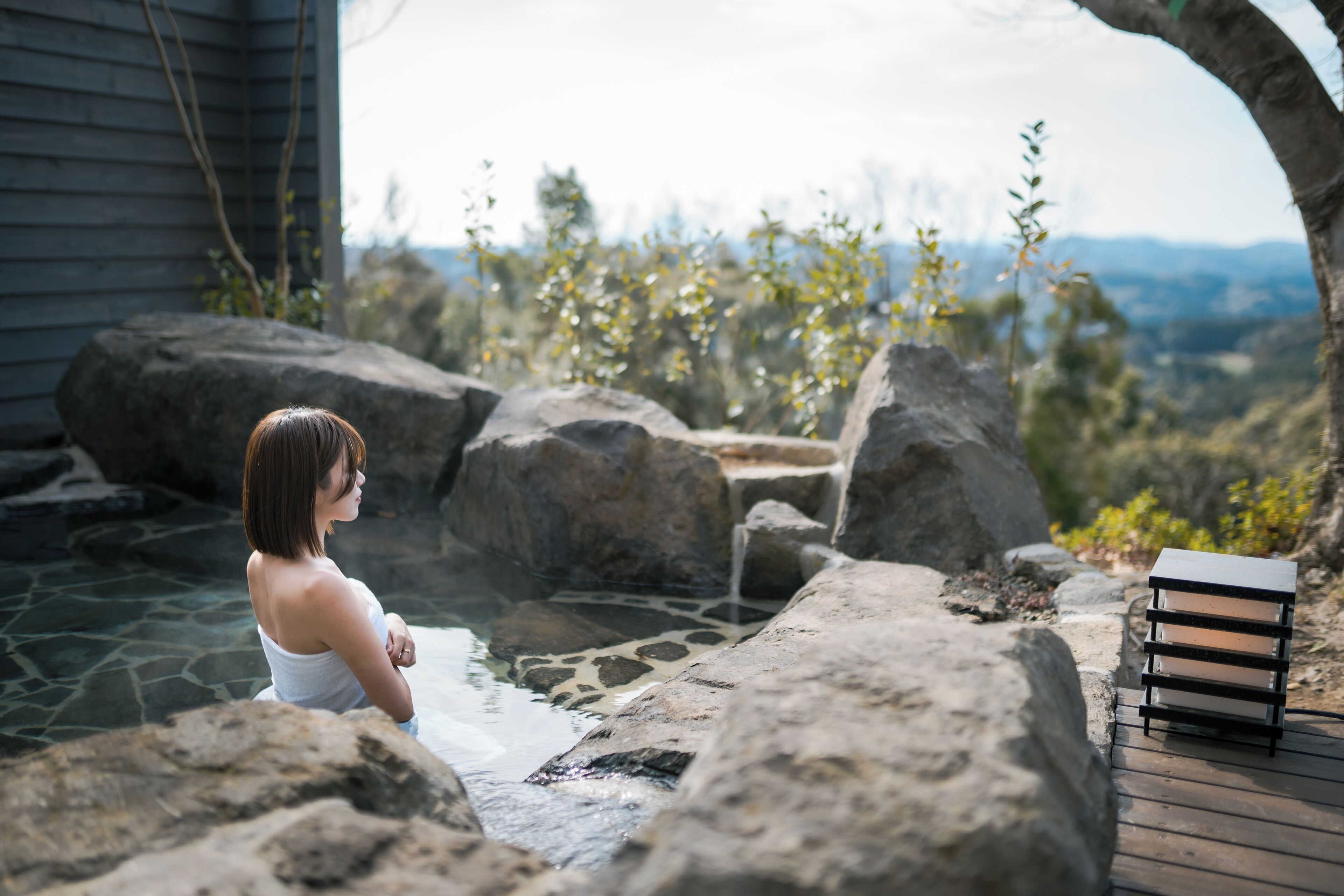 A spa area with a hot spring, large rocks, and a wooden deck.