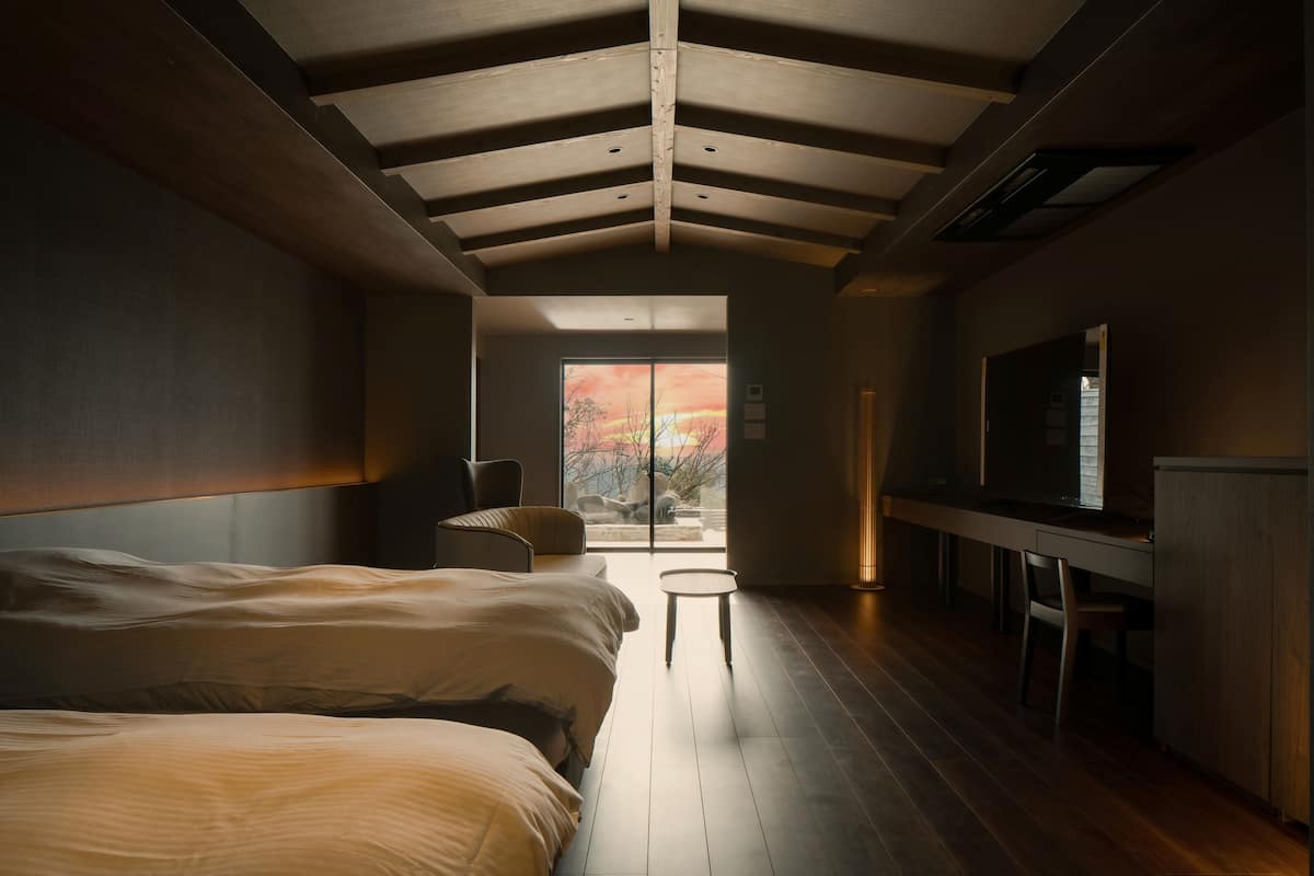 A modern bedroom with a large bed, a desk, and a TV.