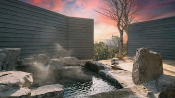 A spa area with a hot spring, wooden deck, and a tree.