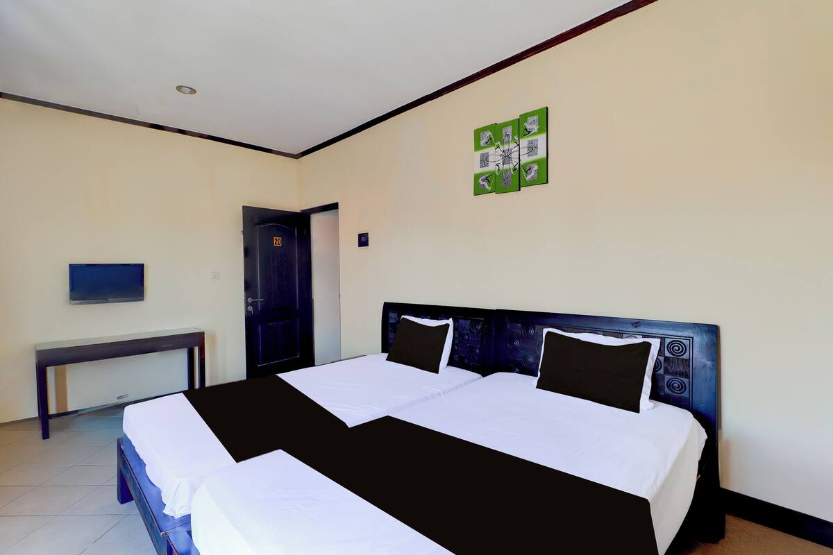 A hotel room with a large bed, a desk, and a television on the wall.