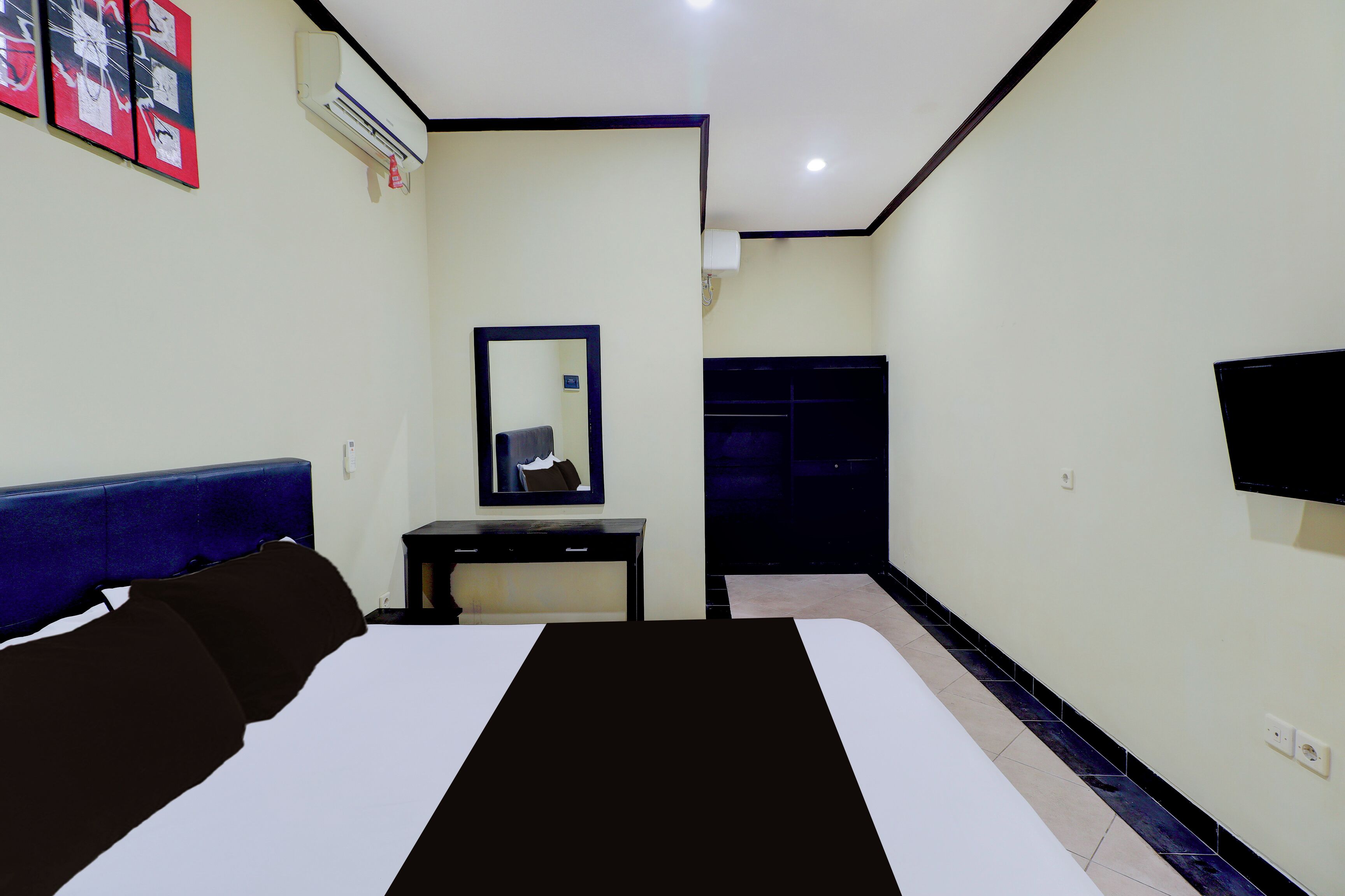 A hotel room with a bed, a desk, a mirror, a wardrobe, and a TV.