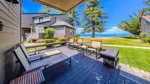A covered outdoor deck with seating, overlooking a beach and a residential area.