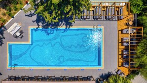 An aerial view of a rectangular swimming pool with a surrounding deck, lounge chairs, and a covered seating area. - Trees Art Hotel & Suites (Rhodes)