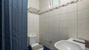 A bathroom with a toilet, sink, and blue-tiled floor. - Trees Art Hotel & Suites (Rhodes)