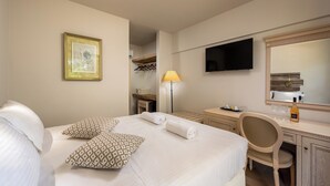 A hotel room with a bed, a desk, a chair, a television, and a mirror. - Trees Art Hotel & Suites (Rhodes)