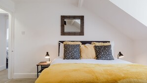 A bedroom with a bed, a nightstand, a lamp, a mirror, and a door. - Modern contemporary dog friendly - Licata's Apartment (Cirencester)