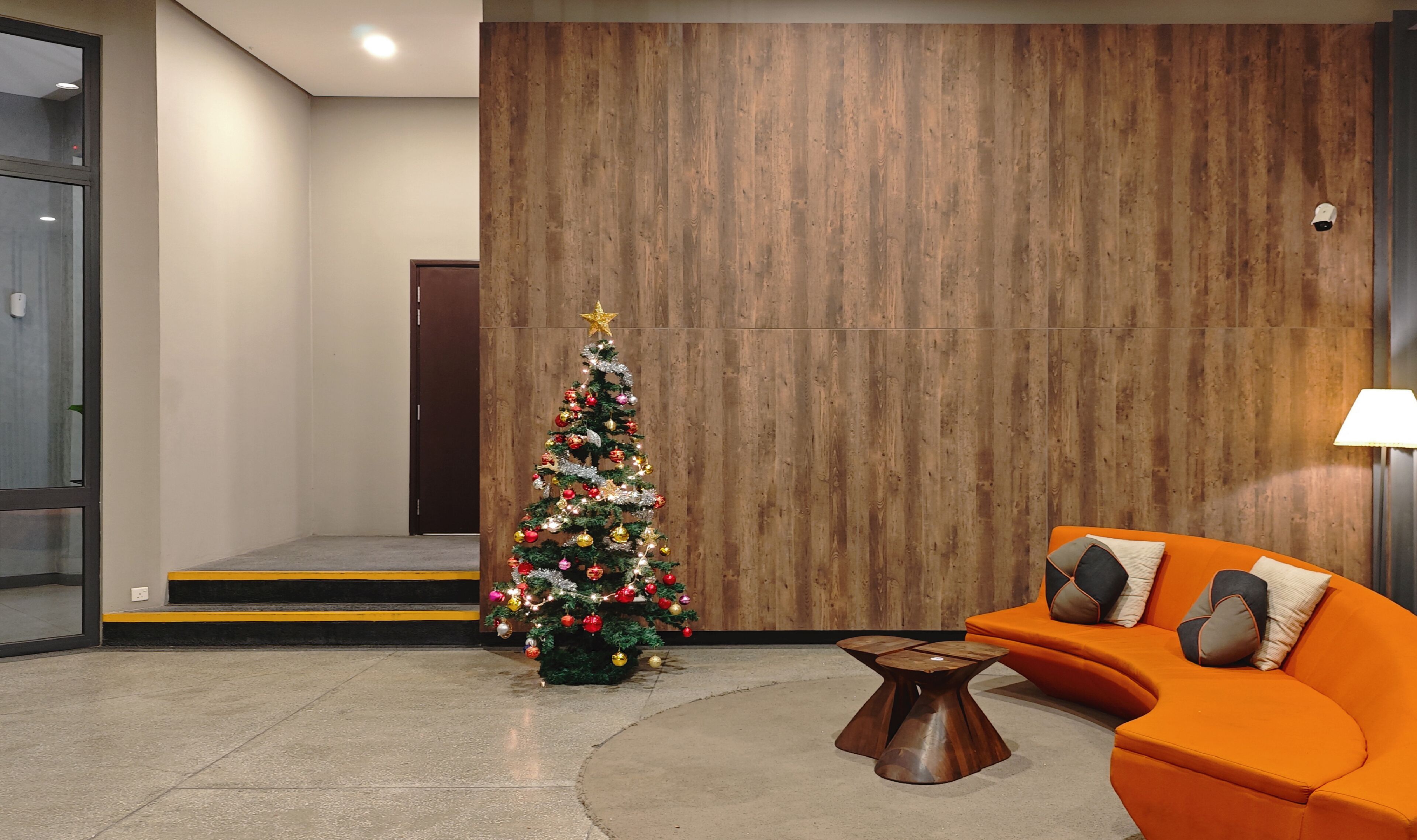 Un vestíbulo moderno con una pared de madera, un árbol de Navidad y un sofá naranja.