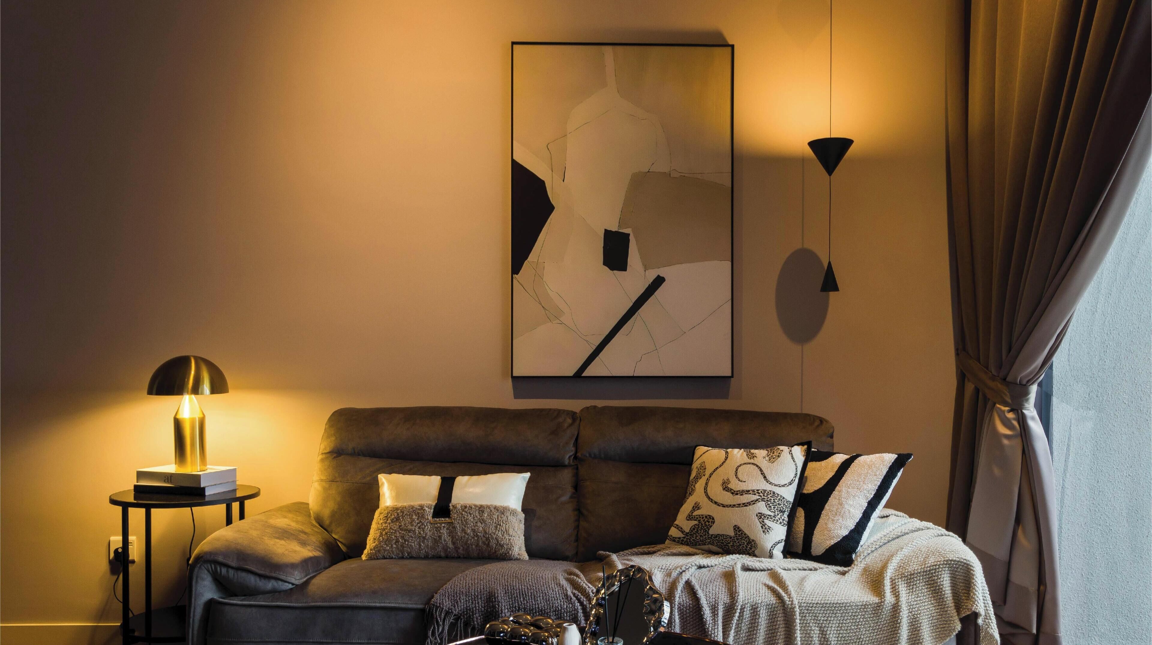 A modern living room with a sofa, decorative pillows, a wall-mounted abstract painting, and a floor lamp.