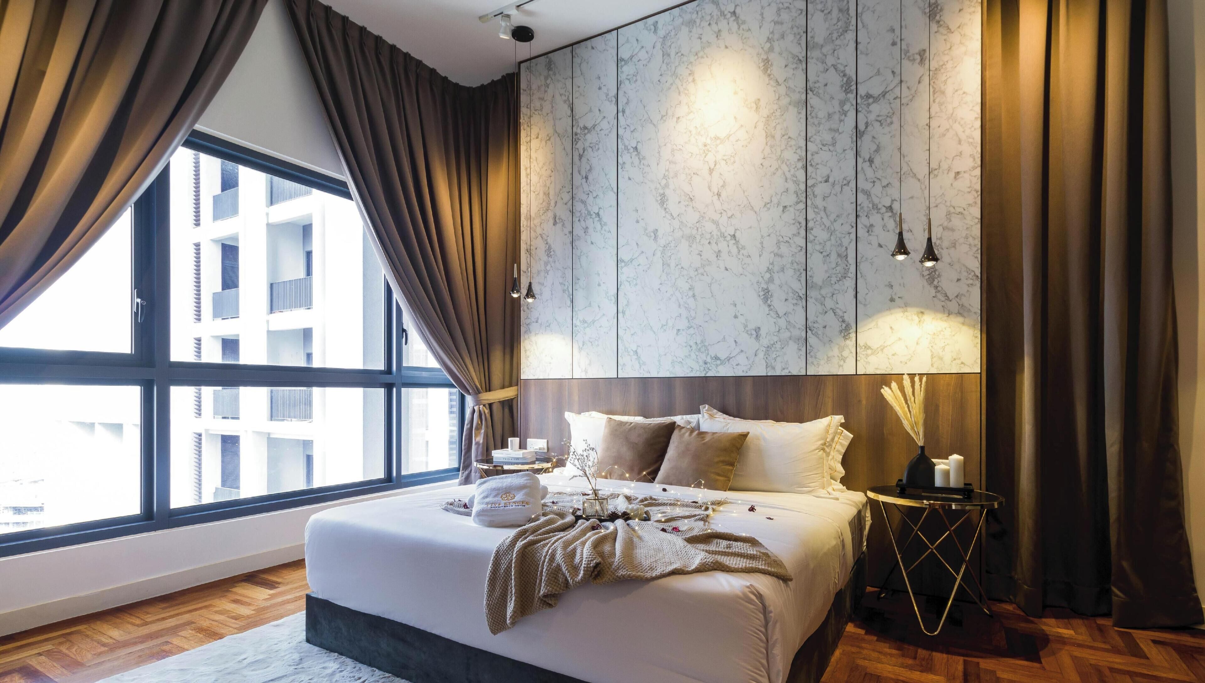 Une chambre d’hôtel moderne avec un grand lit, une table de chevet, un vase et une vue sur les bâtiments par la fenêtre.
